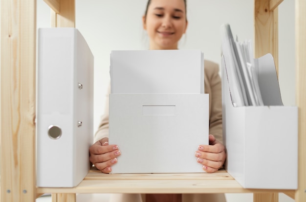 Personne assise a un bureau qui trie des documents administratifs dans des pochettes et classeurs