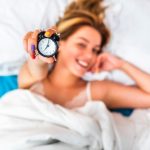 Personne allongée dans son lit qui regarde son réveil au milieu de la nuit